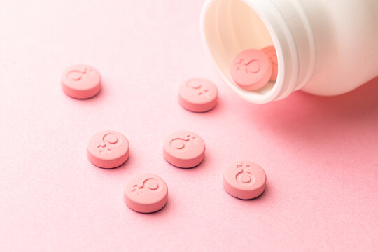 Female gender symbol on pink pills. Pills for women. Contraceptives or during menstruation.
