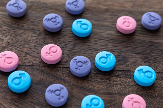 Hormonal pills. Gender symbols of man, woman and transgender. Colored tablets of blue, pink and purple color