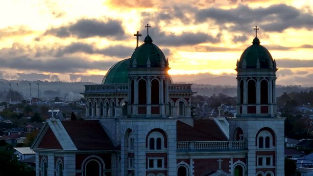 Basilica Sacred Heart in Timaru, aerial close up, dramatic sunset over towers with cross. New Zealand cityscape