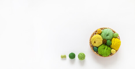 Banner with empty space for text on white background of basket with skeins of wool and cotton yarn for knitting in yellow and green. Summer craft, DIY concept. Top view, copy space, flat lay, blank