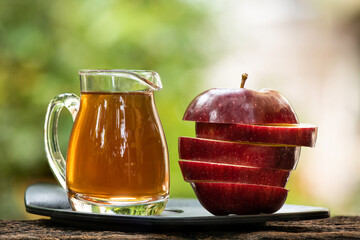 Apple fruit and apple cider vinegar on nature background.