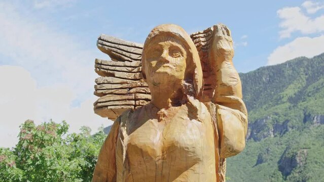 Closeup footage of a wooden statue with mountains in the background in Terragnolo, Trentino