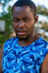 Vertical shot of a black bold man in blue t-shirt outdoors