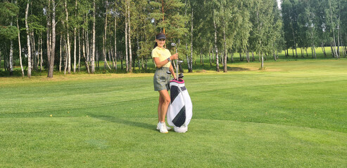 Beautiful woman golfer holding a golf bag