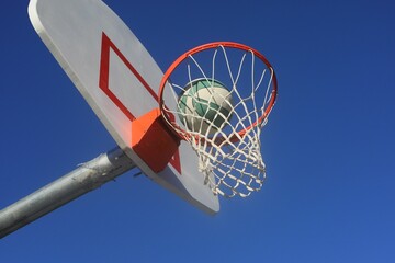 Basketball going through the hoop with a blue sky in the background