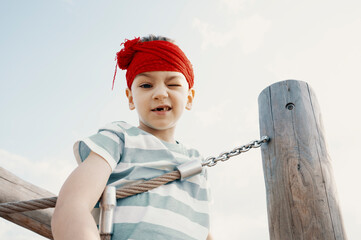 A little boy dressed as a pirate plays on a wooden playground