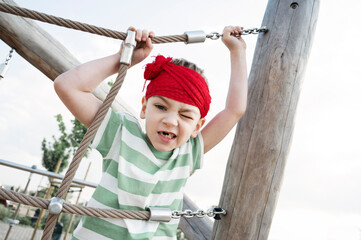 A little boy dressed as a pirate plays on a wooden playground
