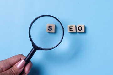 Magnifying glass focus on S letter of SEO word, Search Engine Optimization on a blue background.