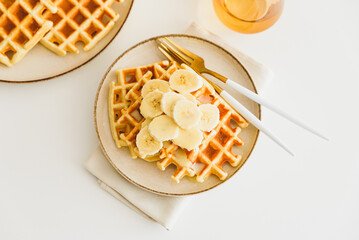 Belgian waffles with banana and condensed milk on white table. Top view