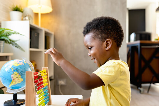 A cute little African child plays with a colorful wooden abacus toy. Educative toys.