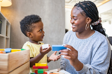 A cute little African child plays with colorful didactic educational toys. His proud mother...