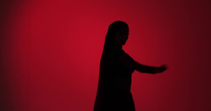 Against a striking red background, a young woman's fluid silhouette moves with energy and expression, showcasing the beauty and depth of Indian classical dance.
