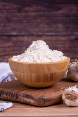Fototapeta na wymiar Garlic powder on wooden background. Dried ground garlic powder spices in wooden bowl. Close up
