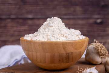 Garlic powder on wooden background. Dried ground garlic powder spices in wooden bowl. Close up