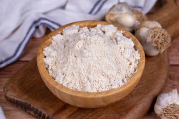 Fototapeta na wymiar Garlic powder on wooden background. Dried ground garlic powder spices in wooden bowl. Close up