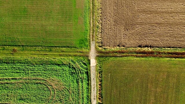 Crossing of dirt roads with several fields seen from a drone point of view while rotating directly from above