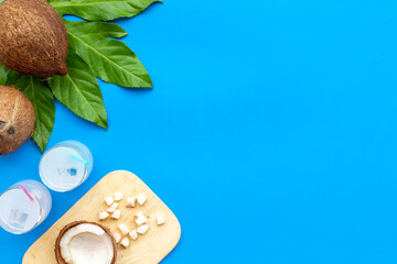 Coconut milk cocktail with ice in two glasses with green palm leaves