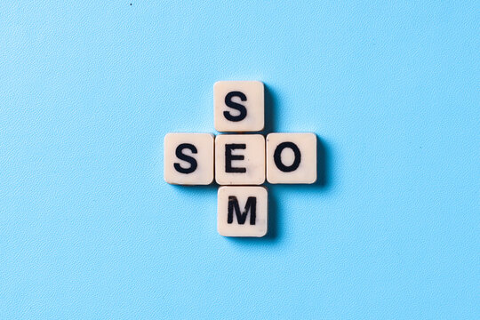 Wooden cubes with the word SEO and SEM isolated on blue background. Search Engine Marketing and Search Engine Optimization. 