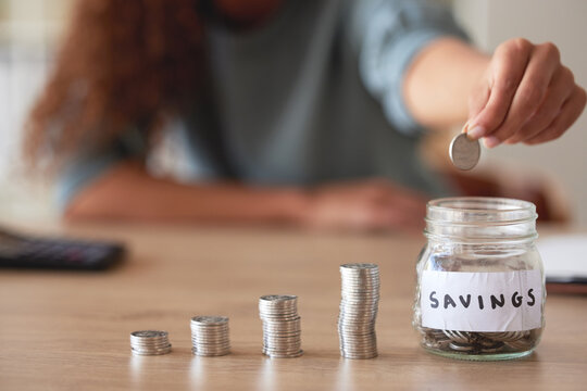 Hand, savings jar and money with finance and budget, future financial planning with investment and coins on a table. Woman saving, payment and economy, growth and development, cash in glass container