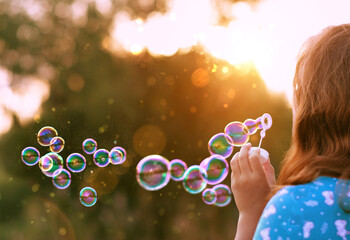 abstract blurred sunny natural background with girl blowing soap bubbles outdoor. dreaming, harmony peaceful atmosphere. Happy childhood concept. template for design - obrazy, fototapety, plakaty