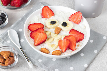 Sweet oatmeal in the shape of an owl with strawberries, banana, almonds and coconut flakes, idea breakfast for kids