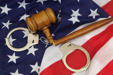 Injustice and wrong court verdict in USA. Broken gavel with handcuffs on US flag.