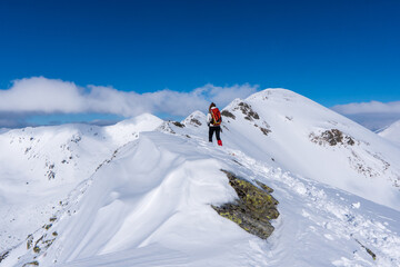 Fototapeta na wymiar Active woman snow shoe hiking on a trail with scenic view on snow capped mountain peaks of West Tatras mountain in Slovakia, Europe. Julian Alps. Sunny winter day. Freedom.