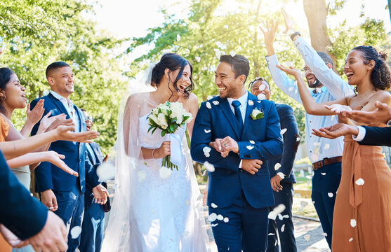 Happy, wedding ceremony and couple walking with petals and guests throw in celebration of romance. Romantic, flowers and bride with bouquet and groom with crowd celebrating at outdoor marriage event.