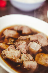 Braised pork or stewed pork in a white bowl that is popular in Thailand eating with rice or noodles. Close up