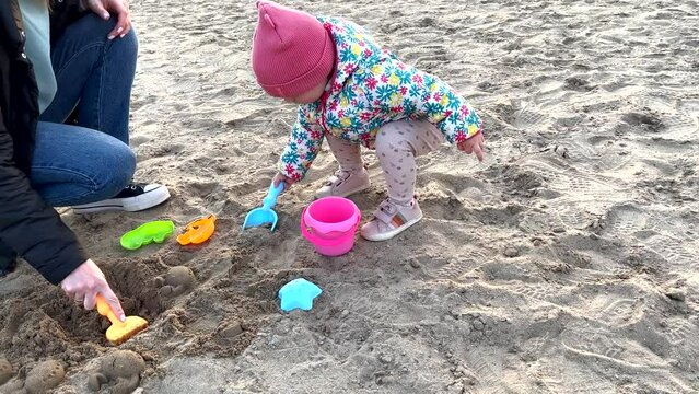 A child with mother are playing in the sand