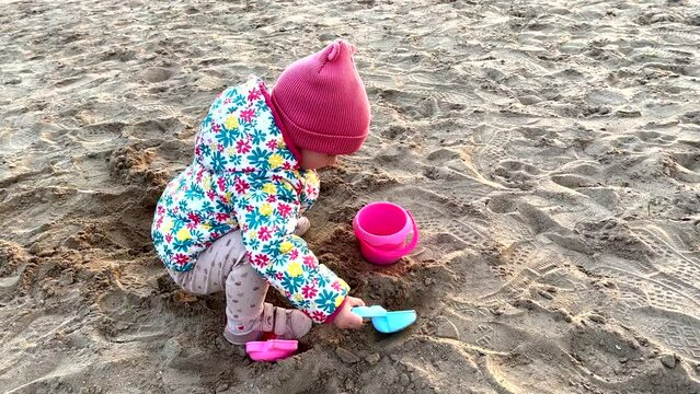A little girl is playing in the sand on the coast