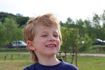 Portrait of a shaggy boy with blond hair and a sly look. Joyful six year old boy.