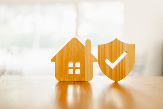  Wooden house model and real estate insurance ideas, and small shield icon. Housing insurance against impending loss and fire, building fire insurance concepts.