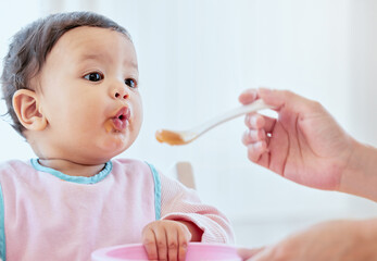 Mother, feeding baby girl and spoon in home, kitchen or living room for nutrition, growth or...