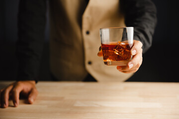 Young man holding whiskey glass in bar or restaurant.