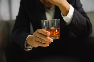 Young man holding whiskey glass in bar or restaurant.
