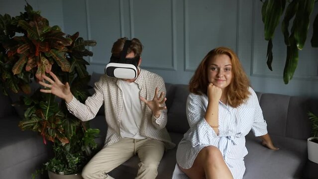 Man playing in virtual 3D glasses reality and his angry sad wife near him