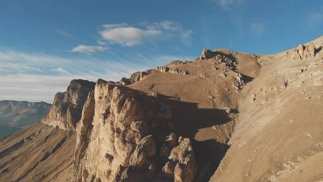 drone flies along the steep slopes of the rocky mountain peaks and along the picturesque stone canyon on a sunny day