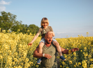 A man and a boy are walking in a rapeseed field