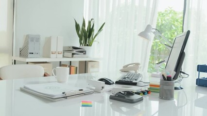 No people shot of workplace of insurance agent in office with white desk, desktop computer and piles of documents in folders on it