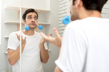 Handsome man standing in front of the mirror and doing facial massage with vacuum cups. Skin care...