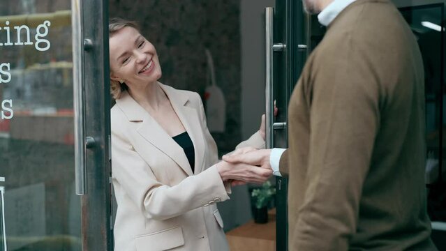 Video of twp mature business people shaking their hands while smiling after signing new contract in modern startup office.