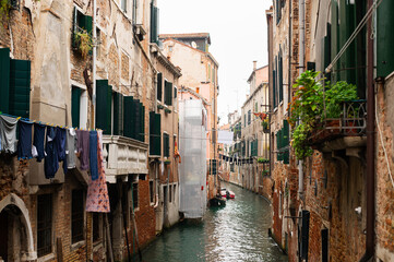 Narrow canals of Venice city with old traditional architecture, bridges, boats and drying clothes, Veneto, Italy. Tourism concept. Architecture and landmark of Venice. Cozy cityscape of Venice.