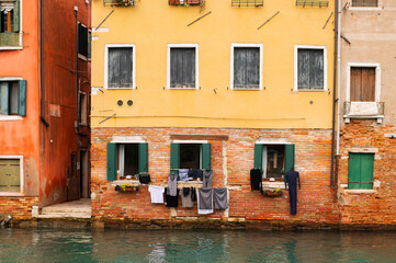 Fototapeta na wymiar Narrow canals of Venice city with old traditional architecture, bridges, boats and drying clothes, Veneto, Italy. Tourism concept. Architecture and landmark of Venice. Cozy cityscape of Venice.