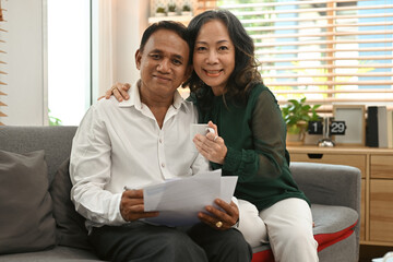 Asian retired couple smiling happily inside their home, Elderly Fund, Pension retirement insurance concept.