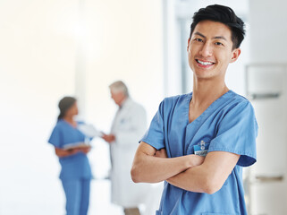 Portrait, happy man and Asian nurse with arms crossed in hospital or clinic. Face, confidence and medical professional, male surgeon or doctor with pride for career, job and healthcare for wellness. - Powered by Adobe