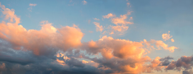 sunset panorama sky with yellow lighted cumulus clouds and blue above.