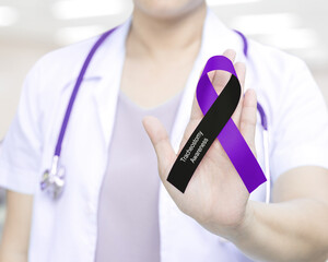 Female doctor in white uniform with black and purple ribbon awareness in hand as stop sign for ...