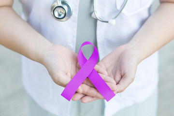 Purple awareness of ribbon in doctor hand for Cancer, ADD,ADHD,Alzheimer's Disease ,Arnold Chiari Malformation,Childhood Hemiplegia & stroke, Epilepsy, Chronic & Acute Pain,Crohns - obrazy, fototapety, plakaty