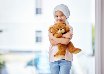 Fototapeta Healthcare, child and portrait of a cancer patient holding a teddy bear for support or comfort. Medical, smile and girl kid with leukemia standing with a toy after treatment in a medicare hospital. obraz